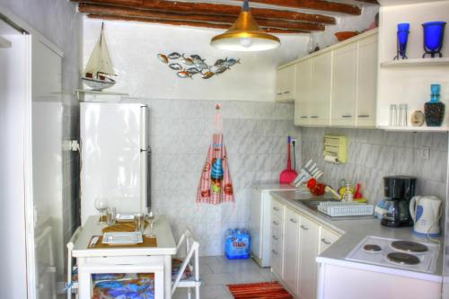 a kitchen with white cabinets and a white refrigerator at The Hot Pink Bike House in Parikia