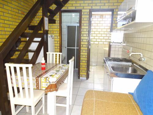 cocina con mesa, sillas y fregadero en Apto Duplex Bombinhas, en Bombinhas