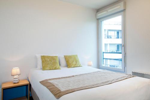 een witte slaapkamer met een groot bed en een raam bij Séjours & Affaires Clermont Ferrand Park République in Clermont-Ferrand