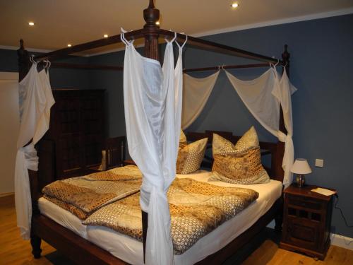 a bedroom with a canopy bed with curtains on it at Gästehof Cafe im Schafstall in Barsinghausen