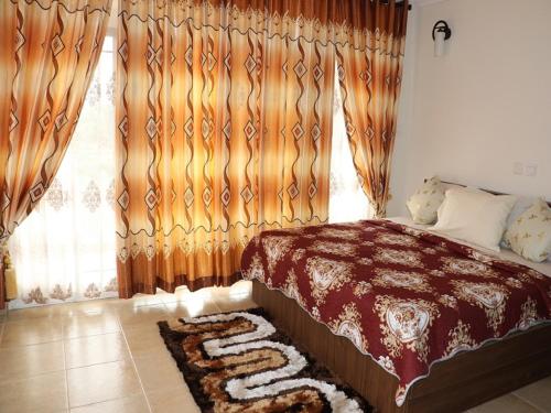 a bedroom with a bed and a window with curtains at Jaria Apartments in Accra