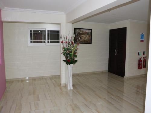 a vase of flowers in a room with a door at Jaria Apartments in Accra