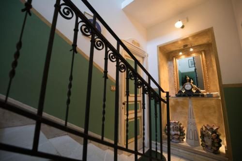 a hallway with a staircase with a clock and a mirror at Cannatella's Mansion in Palermo