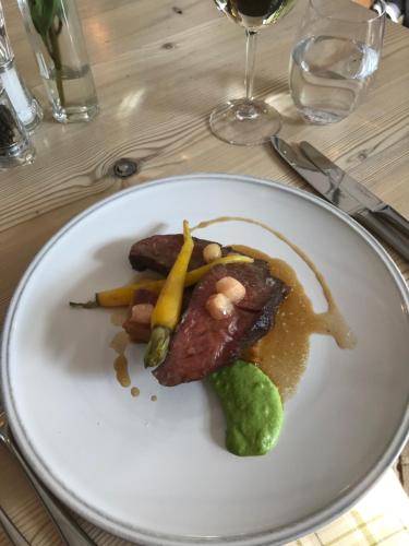 a white plate with meat and vegetables on a table at The Dog At Wingham in Wingham