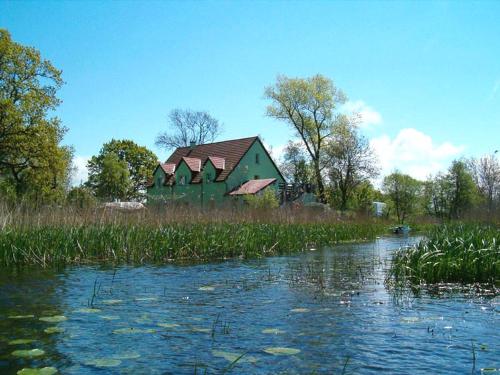 a green house is sitting next to a river at Green Gables in Mrzeżyno