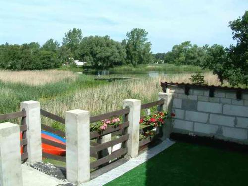 a fence next to a field with a pond at Green Gables in Mrzeżyno