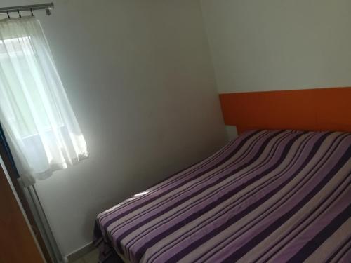 a bedroom with a striped bed with a window at Bungalow Gambaro 2 in Cavallino-Treporti