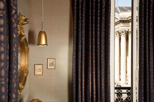 a room with a curtain and a window with a building at Hôtel Les Dames du Panthéon in Paris