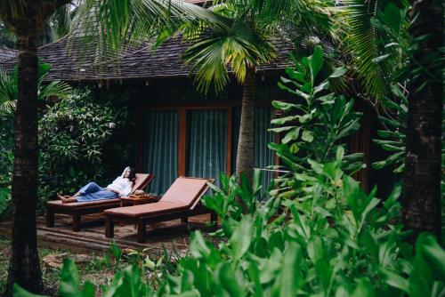 a woman sitting on a chair in front of a house at Andalay Beach Resort Koh Libong in Ko Libong
