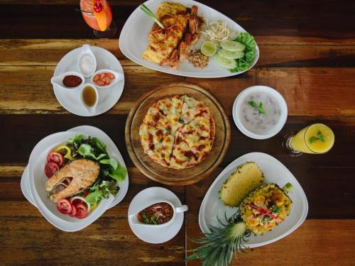 a wooden table with plates of food on it at Andalay Beach Resort Koh Libong in Ko Libong
