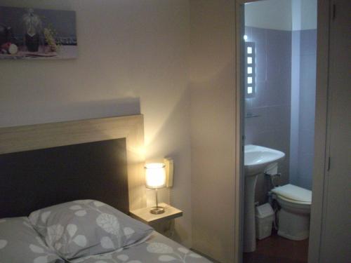 um quarto com uma cama, um lavatório e um candeeiro em Hôtel Restaurant Anglade em Le Nayrac