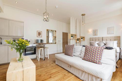 a living room with a white couch and a kitchen at Accudo House Boutique Holiday Suites in Portsmouth