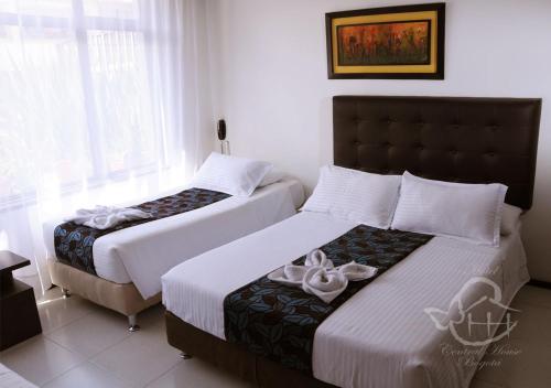 two beds in a hotel room with white walls at Hotel Central House a 5 min de la Embajada Americana in Bogotá