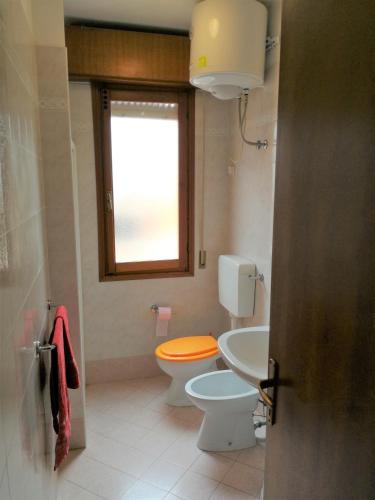 a bathroom with a toilet and a sink and a window at Residence Solarium bilo in Bibione
