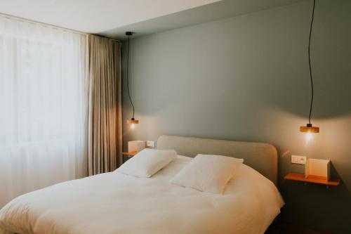 a bedroom with a white bed with two pillows at Hotel Jerom in Kalmthout