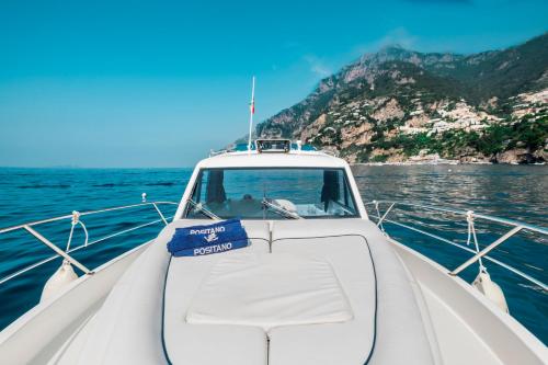a white boat on the water with mountains in the background at Casa TerryB - il Monticello in Positano