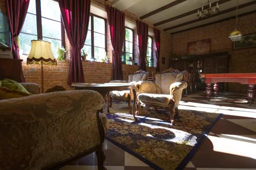 een woonkamer met stoelen, een tafel en ramen bij Akmenių Dvaras in Akmeniai