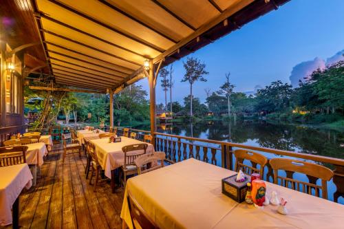 a restaurant with tables and chairs next to a river at Vana Varin Resort in Hua Hin