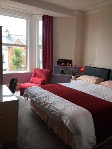 a bedroom with a bed and a chair and a window at Adelphi Guest House in Douglas