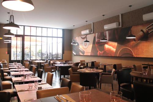 un restaurant avec des tables et des chaises et une grande fenêtre dans l'établissement Les chambres d'hôtes du Fil Rouge, à Armentières