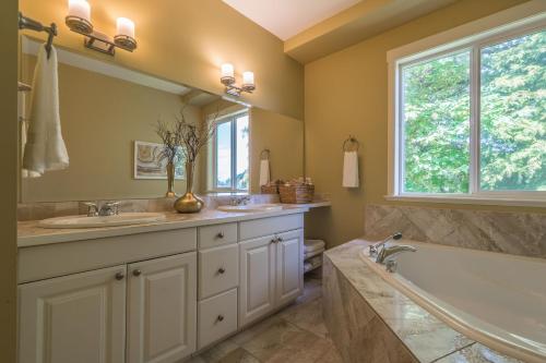 uma casa de banho com 2 lavatórios, uma banheira e uma janela em Luxury Penthouse Downtown Nanaimo em Nanaimo