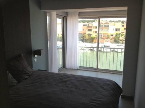 une chambre avec un lit et une grande fenêtre dans l'établissement Les Satines, à Gruissan