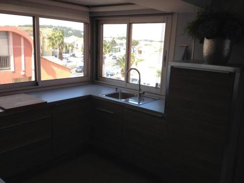 une cuisine avec un évier et une fenêtre dans l'établissement Les Satines, à Gruissan