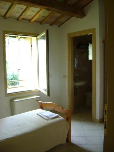 a bedroom with a bed and a window and a bathroom at Fondo Riso in Faenza