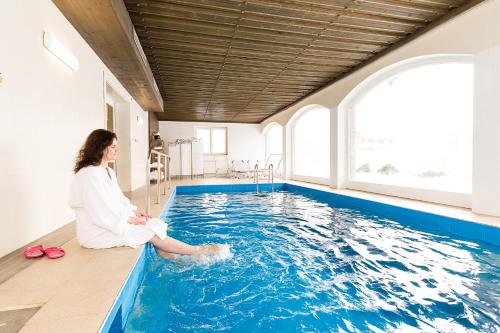 a woman sitting on the edge of a swimming pool at Almerwirt in Maria Alm am Steinernen Meer