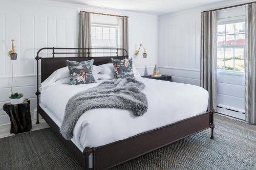 een slaapkamer met een bed met een deken en kussens bij The Coonamessett in Falmouth