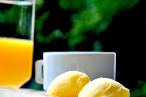 a piece of bread next to a cup of orange juice at Hotel Platanus in Campos do Jordão