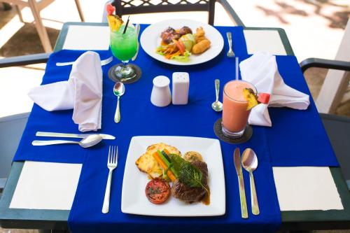 a blue table with plates of food and a drink at Merrils Beach Resort II in Negril