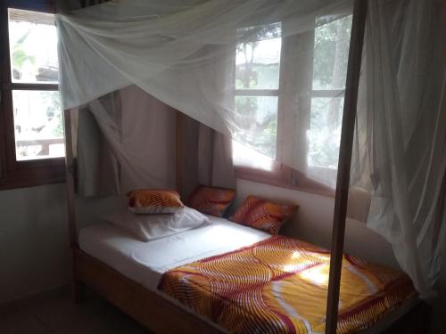 1 dormitorio con 1 cama con dosel y 2 ventanas en Jardin d'Afrique, en Saly Portudal
