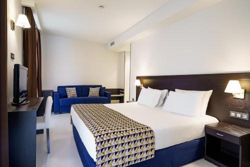 a hotel room with a bed and a blue couch at Exe Málaga Museos in Málaga