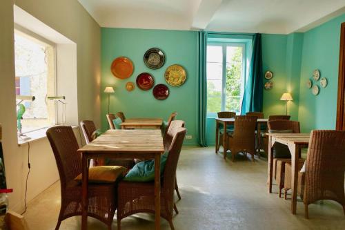 Hôtel de Mirmande في ميرماند: غرفة طعام بجدران خضراء وطاولات وكراسي خشبية