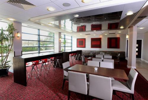 un restaurante con mesas y sillas blancas y un bar en International Hotel Telford en Telford