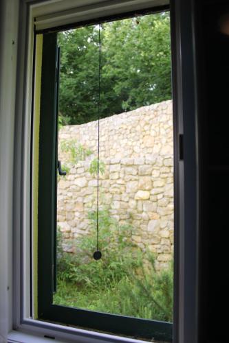 a window with a view of a stone wall at Primavera in Omišalj