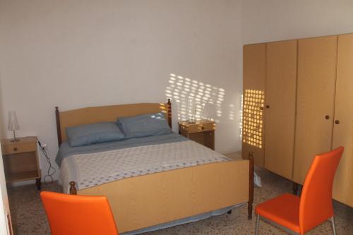 マリーナ・ディ・マンカヴェルサにあるAppartamento vicino al mareのベッドルーム1室(ベッド1台、オレンジ色の椅子2脚付)