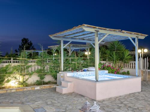 a swimming pool with a pergola at night at Three Graces Holiday Houses Complex in Laganas