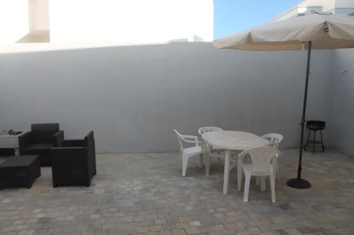 マリーナ・ディ・マンカヴェルサにあるAppartamento vicino al mareのテーブルと椅子、傘が備わります。