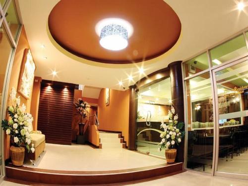 a lobby with a staircase and flowers in a building at The Great Residence Suvarnabhumi Airport in Lat Krabang