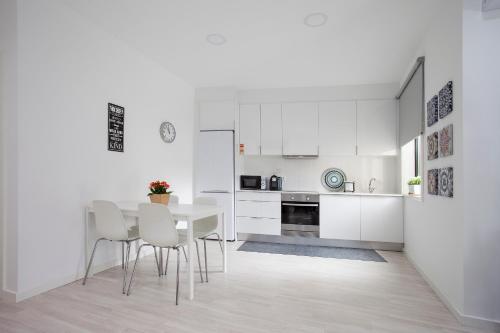 - une cuisine avec des placards blancs, une table et des chaises dans l'établissement Liiiving in Porto | Santa Catarina Cosy Apartment, à Porto