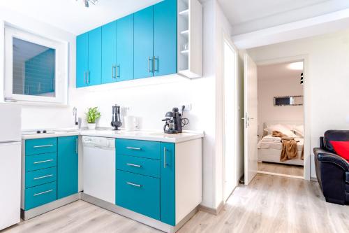 a kitchen with blue cabinets and a bedroom at 2 Apartmans "Metro" and "Gum" in Split