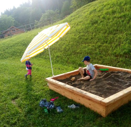 two children playing in a sandbox with an umbrella at Waldner's Ferienwohnung in Hermagor