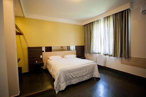 a bedroom with a white bed and a window at Aipana Plaza Hotel in Boa Vista