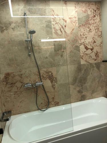 a shower with a glass door next to a bath tub at Dönhoff Residence in Pärnu