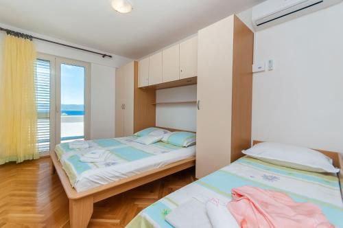 two beds in a room with a view of the ocean at Miran apartments Pisak in Pisak