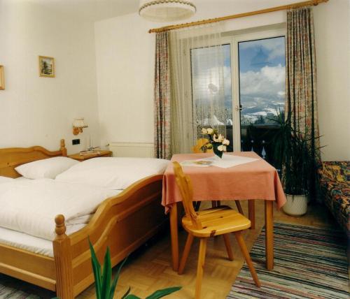 バート・ザンクト・レオンハルト・イム・ラヴァントタールにあるHotel Gasthof Buchbauerのベッドルーム1室(ベッド1台、テーブル、窓付)