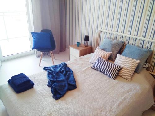 a bedroom with a white bed with pillows and a blue chair at Port Przymorze 909 with the sea view in Gdańsk