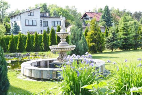 a fountain in a garden in front of a house at Zajazd Bachus in Czarnocin